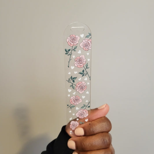A person holding a double-sided UV DTF acrylic bookmark featuring pink roses and small hearts from SuppliedByKai, perfect for floral-themed reading accessories.
